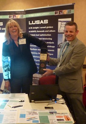 Terry Cakebread of LUSAS holds the container as Valerie Ellington of McClain pulls-out the winning business card.